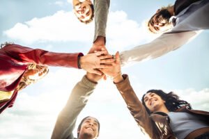 5 Menschen legen ihre Hände über einander und formen einen Stern